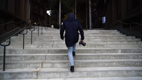 Joven-Fotógrafo-Caucásico-Subiendo-Escaleras-Tomando-Fotos,-Arquitectura-Moderna