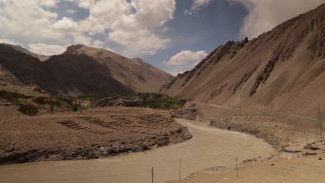 glacial wash flowing through valley with sweeping clouds making shadow and light patterns over the rocky landscape, ladakh region india