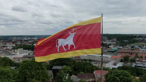 Kaunas-city-flag-waving-above-downtown-rooftops,-close-up-view