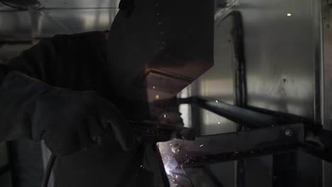 sparks fly and light flickers as welder fabricates metal frame- slow mo, truck right