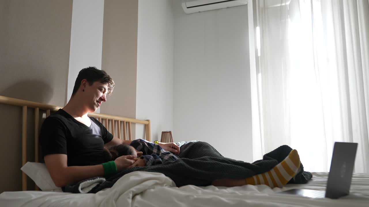 Family relaxing in bed watching laptop