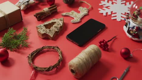 video de decoraciones de navidad y rama de árbol con teléfono inteligente sobre fondo rojo