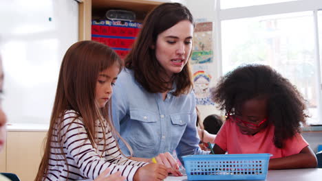 teacher sits with  elementary schoolchildren at art class