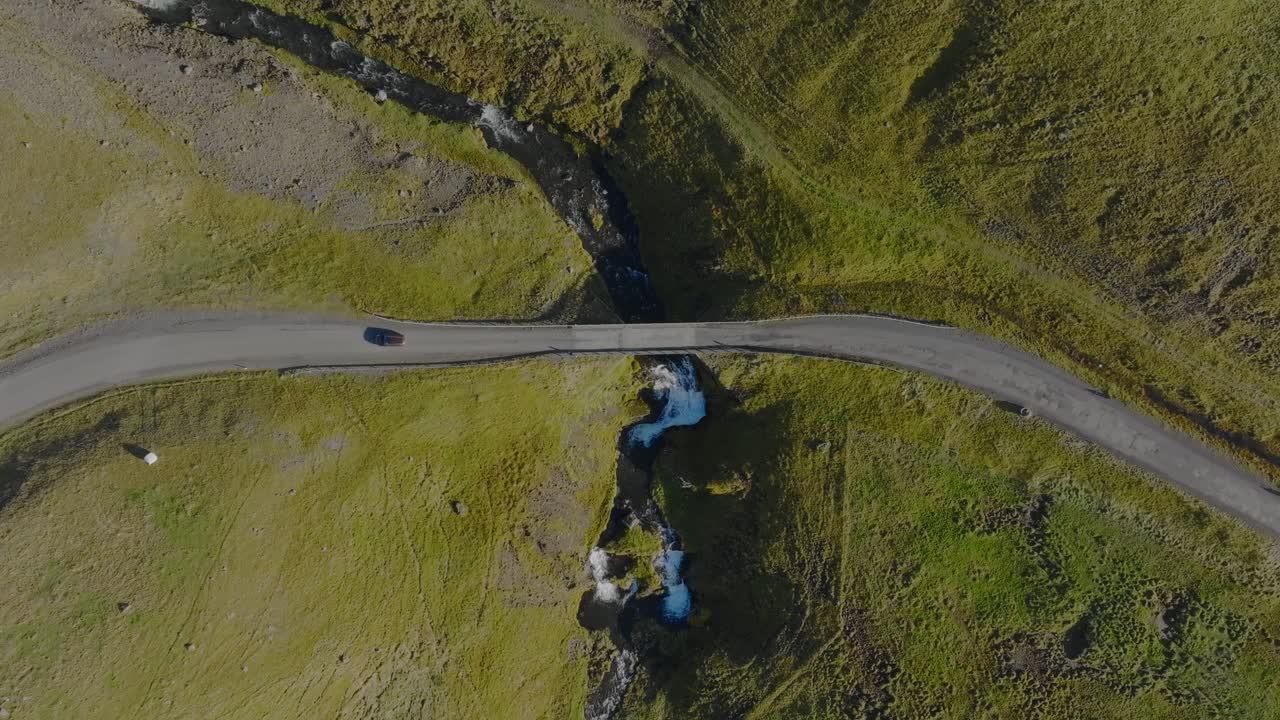 Luftfoto af bil, der kører på malerisk vej og bro i Island, grønt landskab Hvalfjordur