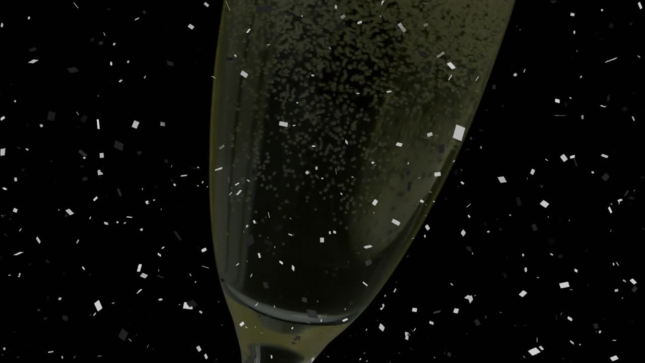 Coriandoli che cadono su un primo piano di bollicine di champagne in un bicchiere su sfondo nero