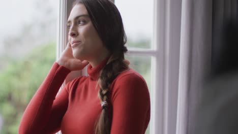 Happy-caucasian-woman-looking-through-the-window,-holding-her-face-and-smiling