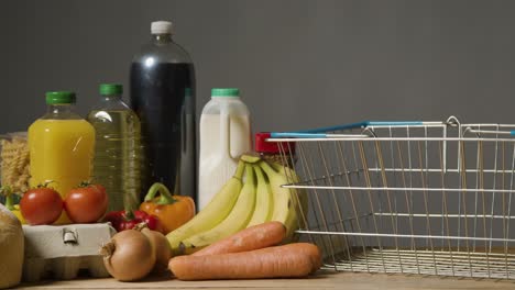 studio shot of basic food items next to supermarket wire shopping basket 3