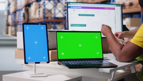 multiethnic team of warehouse workers next to green screen monitor