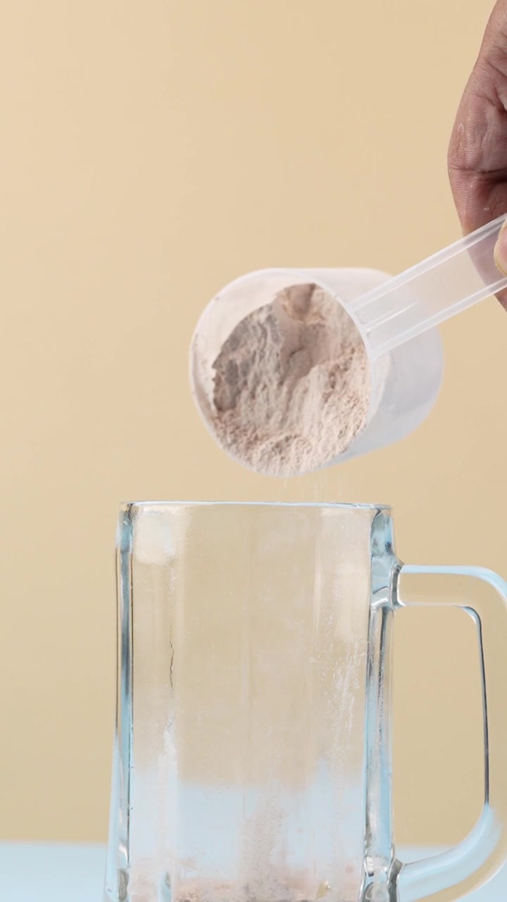 Plantaardig eiwitpoeder dat in een glas wordt gegoten