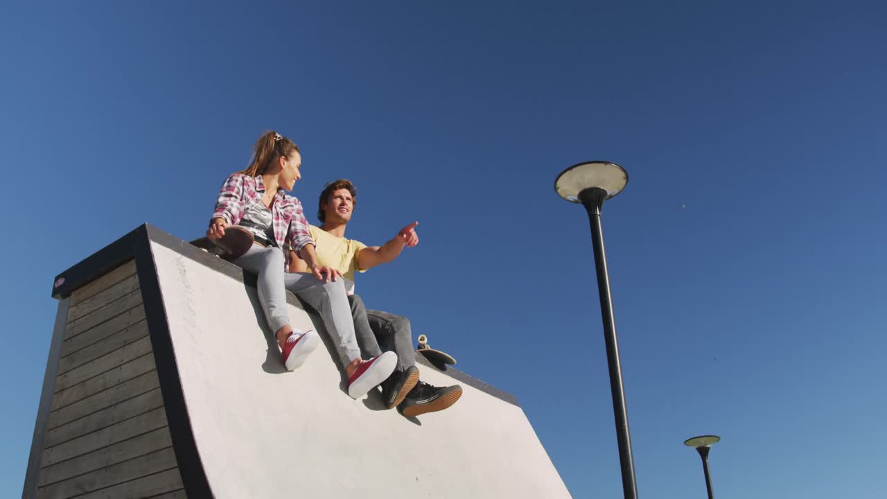 feliz mujer caucásica y amigos hombres con máscara facial, sentados y apuntando a algo en la distancia