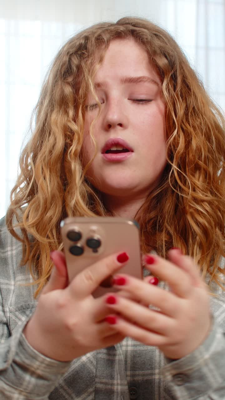 Young woman sitting on sofa holding mobile phone looking sad disappointed after receiving bad news