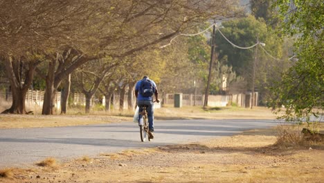 hombre local montando su bicicleta por un barrio