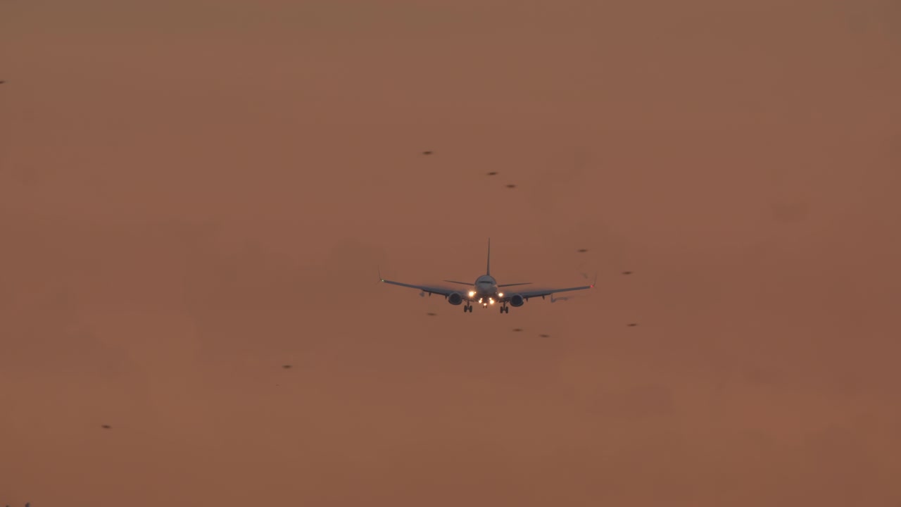 Aereo commerciale in avvicinamento per l'atterraggio in un cielo arancione.