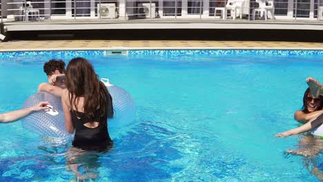 young attractive people swimming on inflatables on the pool party. pretty women and men having a pool party. slowmotion shot