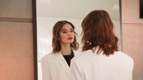 Redhead-woman-enjoys-looking-at-own-reflection-in-big-mirror