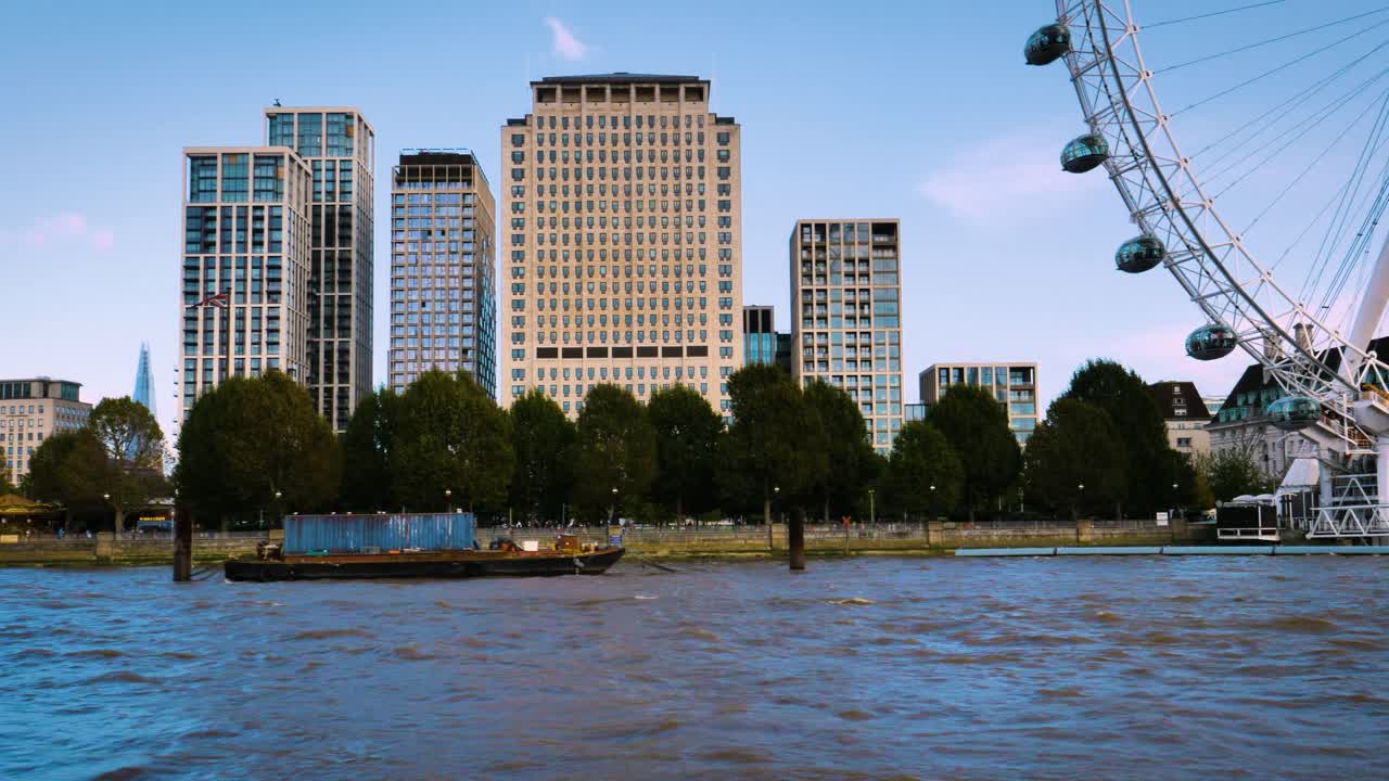 Floating on the river Thames in London on a boat. Passing by iconic skyscrapers of the business district in central London like the Shard and the London Eye, the big wheel in front of Westminster.