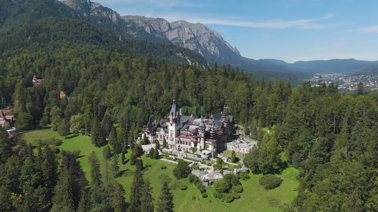 Peleș Castle set in a lush forest, framed by majestic mountains in Sinaia, Romania