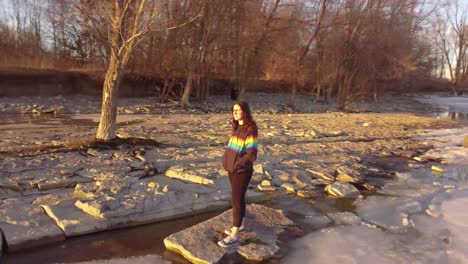 mujeres jóvenes con chaqueta de colores de orgullo en una roca en medio de un lago congelado