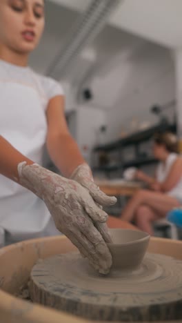 young woman shaping clay on a pottery wheel