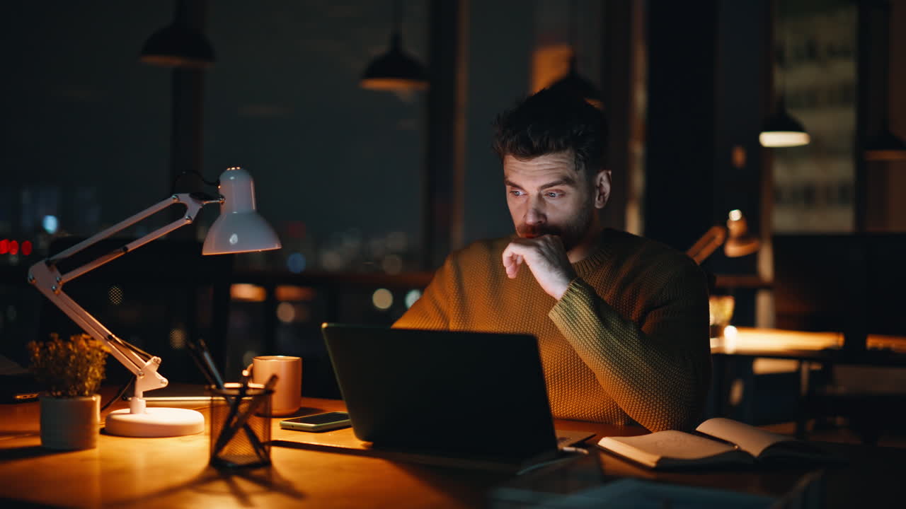 Uomo che lavora fino a tarda notte sul portatile