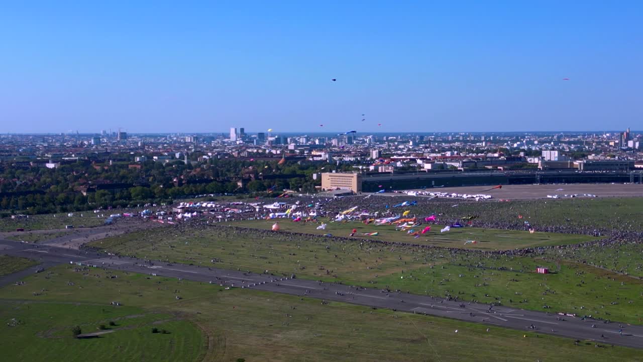 Large crowd of people gathering at the Tempelhofer Feld giant kite festival in Berlin, Germany. Best aerial view flight tilt down drone