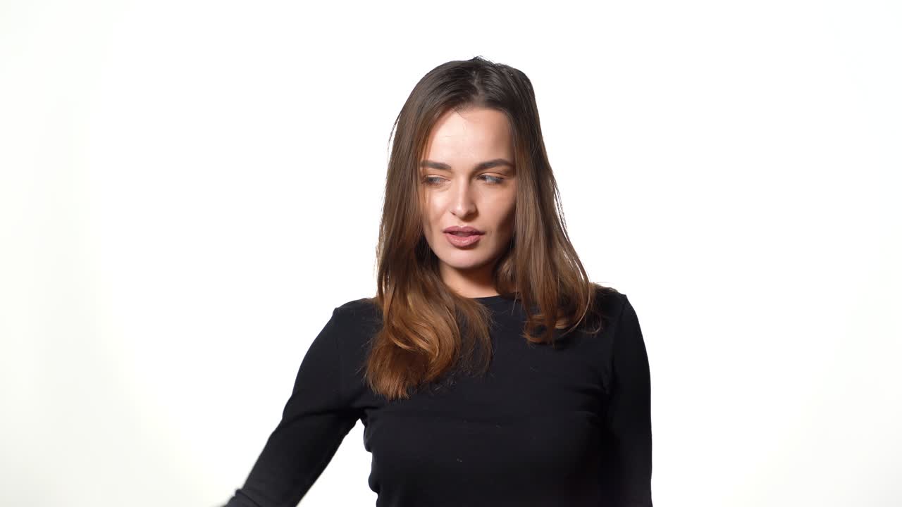 A pretty woman with long hair is holding paper packages in her hands and showing it on a white background in the studio. Shopping