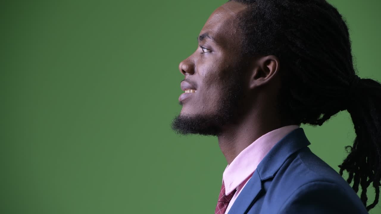 joven empresario africano guapo con dreadlocks contra un fondo verde