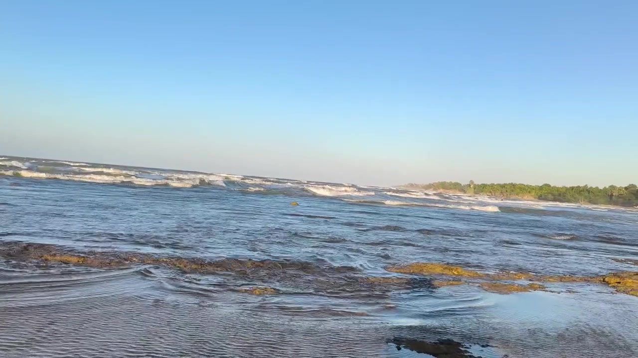 Dolci onde che lambiscono una spiaggia tropicale rocciosa al tramonto