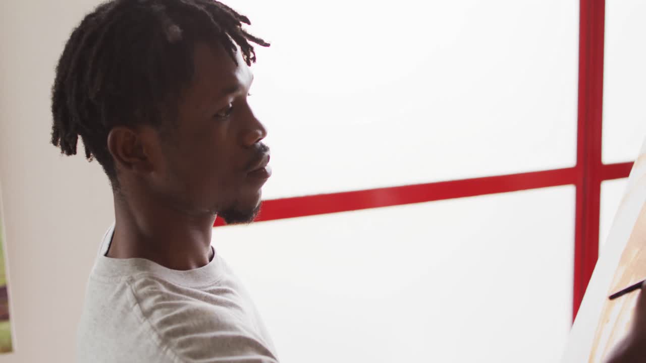 African american male painter painting on canvas in artist studio