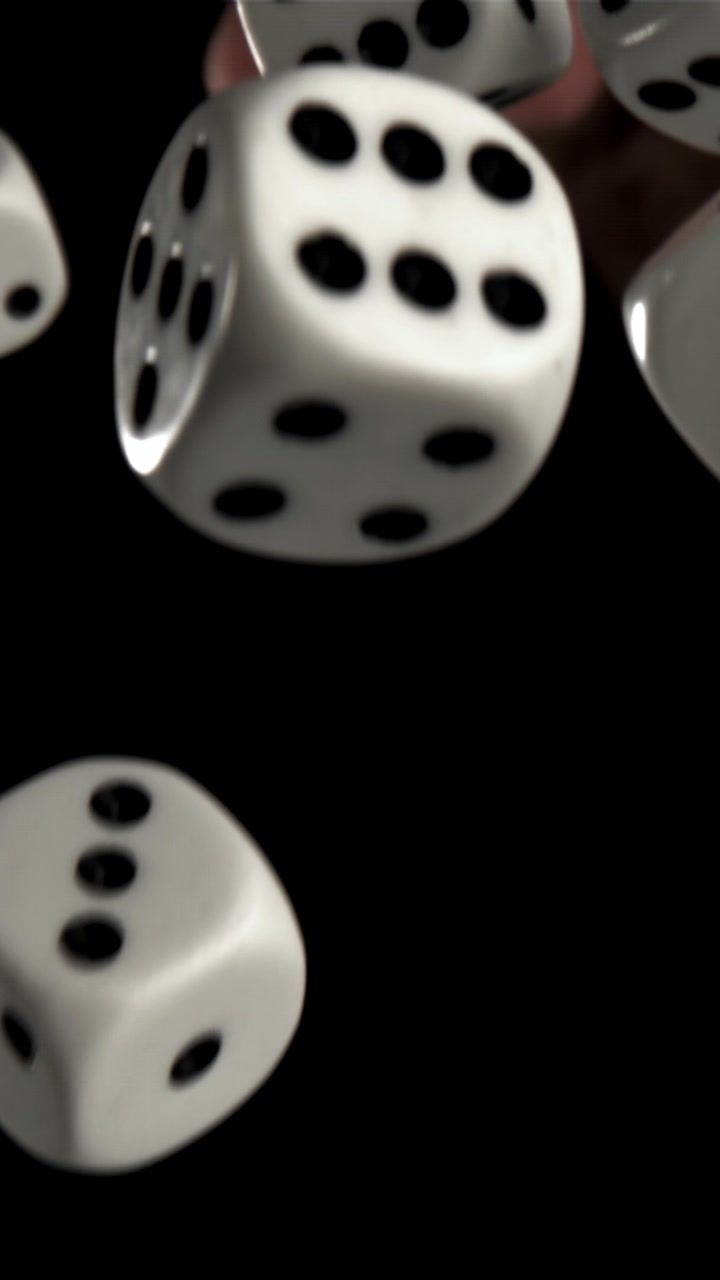 Hvide terninger, der falder i slowmotion mod en sort baggrund.