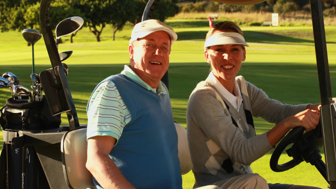 카트 에 앉아 카메라 를 보고 있는 행복 한 부부