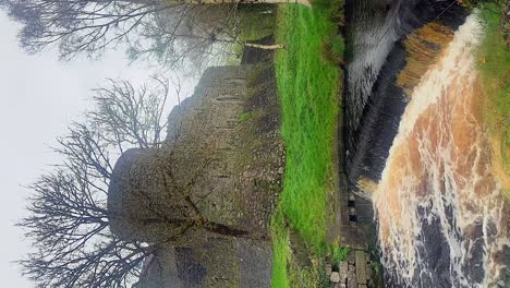 Slow-panoramic-view-of-Athenry-Castle,-picturesque-cascade-in-the-foreground