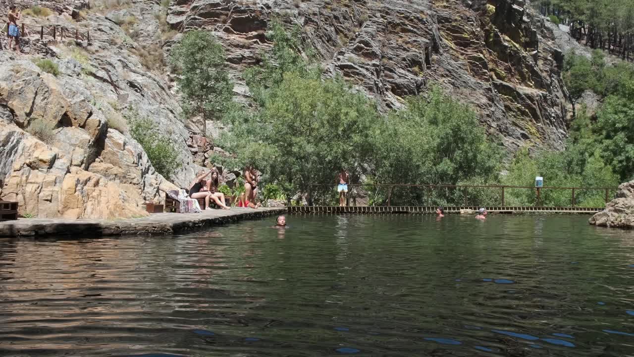 People relaxing in natural pool at Penha Garcia, Portugal. Static view