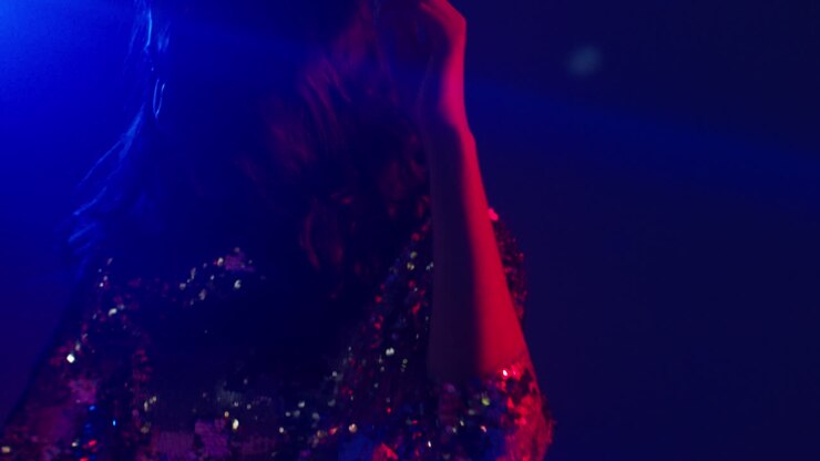 primo piano di una donna in un nightclub o in una discoteca che balla con luci scintillanti 3