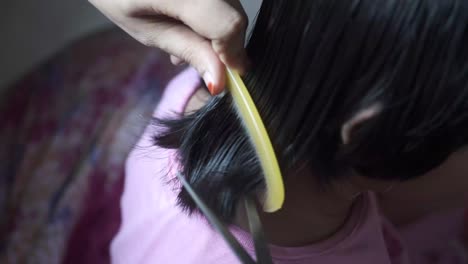 woman cutting a child's hair at home