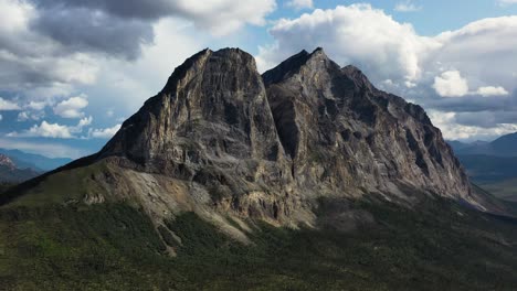 orbiting aerial shot of famous sukakpak mountain against white clouds in summer alaska without snow