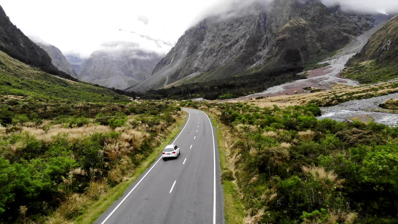 A white Audi A4 driving along the spectacular Milford Road on New Zealand's South Island