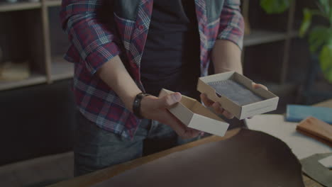 male hands packaging product in cardboard box package in small retail shop