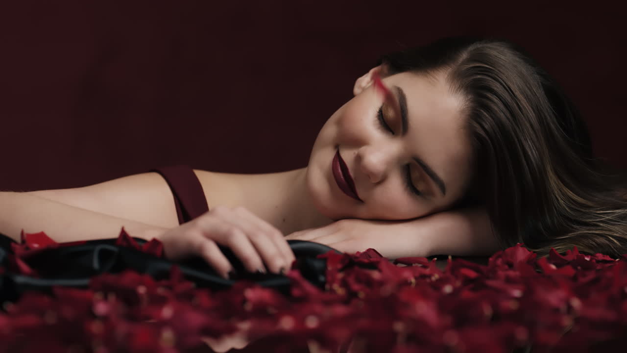 retrato hermosa mujer caucásica jugando con pétalos de rosa cayendo sensual mujer soñando con fantasía íntima romance indulgente deseo en fondo rojo concepto del día de san valentín