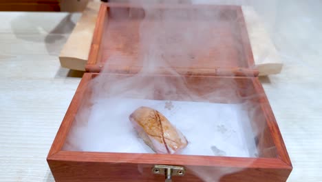 la mano revela sushi en una caja ahumada