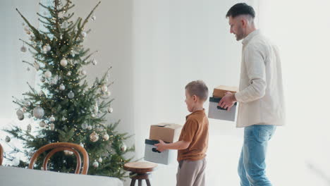 father and son unpacking christmas decorations and decorating tree