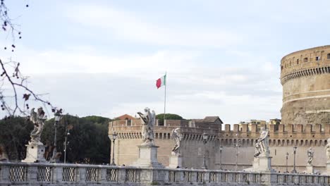 bridge in rome with statues and italian flag