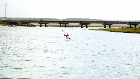 Gesamtaufnahme-Eines-Kanufahrers-Des-Spanischen-Teams-Beim-Rudern-Auf-Dem-Fluss-Barbate-In-Cadiz-Mit-Einer-Brücke-Im-Hintergrund