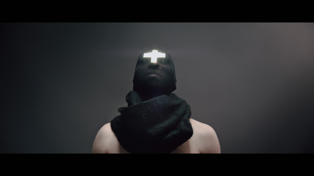 Masked man with cross of light glowing on his face rise head up