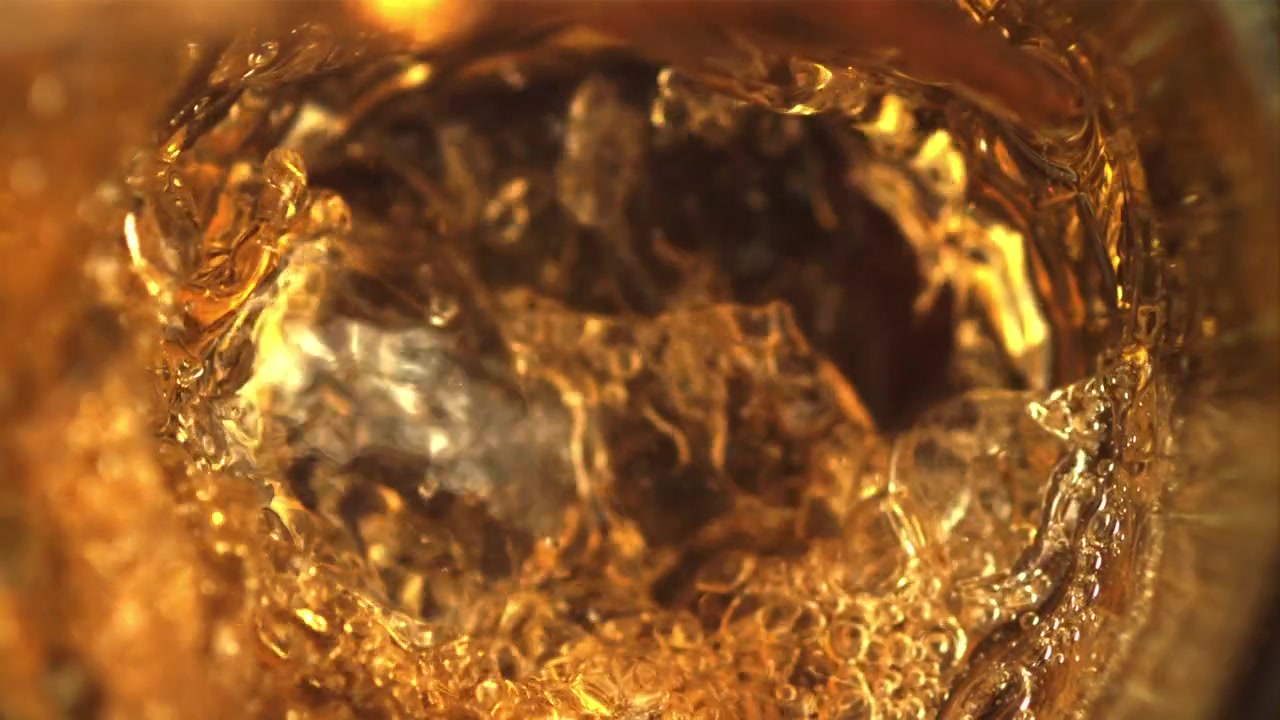 Liquido dorato che si versa in un bicchiere, creando bolle