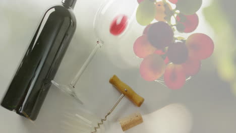 compuesto de botella de vino rojo y vidrio con sacacorchos sobre fondo de uvas