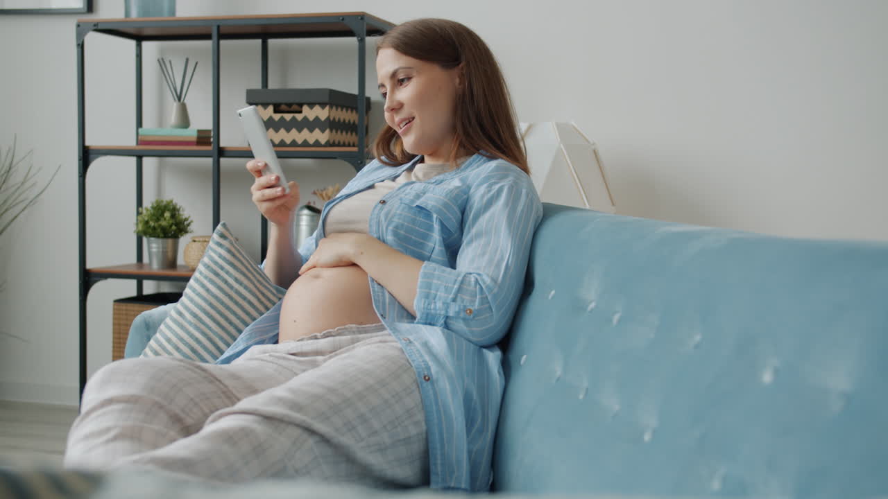 Pregnant Woman Relaxing on Couch with Smartphone