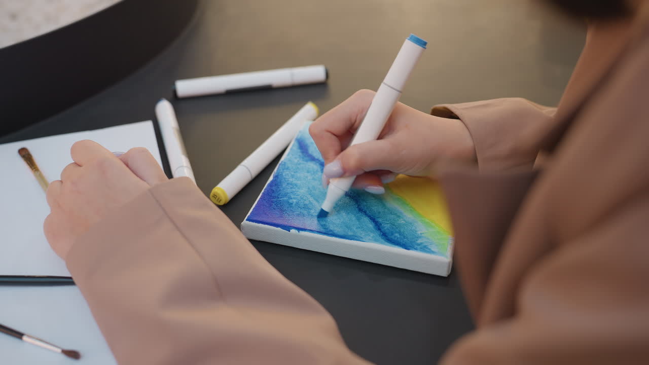 Primer plano de unas manos mezclando colores sobre una superficie texturizada, toma detallada de unas manos mezclando degradados azules con rotuladores, vista cercana de unas manos creando técnicas artísticas de mezcla sobre papel texturizado