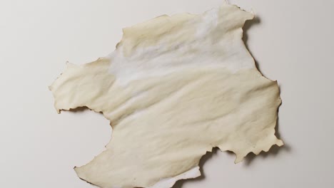 Video-of-close-up-of-piece-of-paper-with-burned-edges-on-white-background