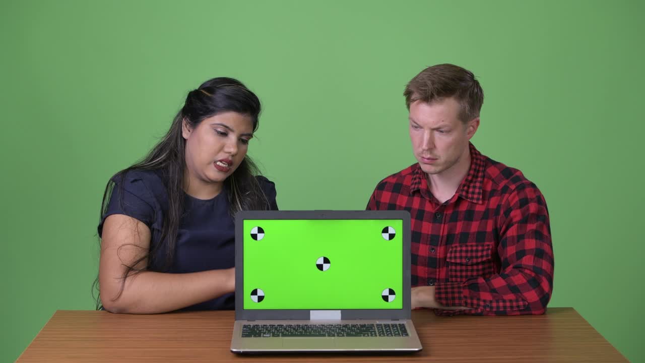 joven pareja de negocios multiétnica juntos contra un fondo verde